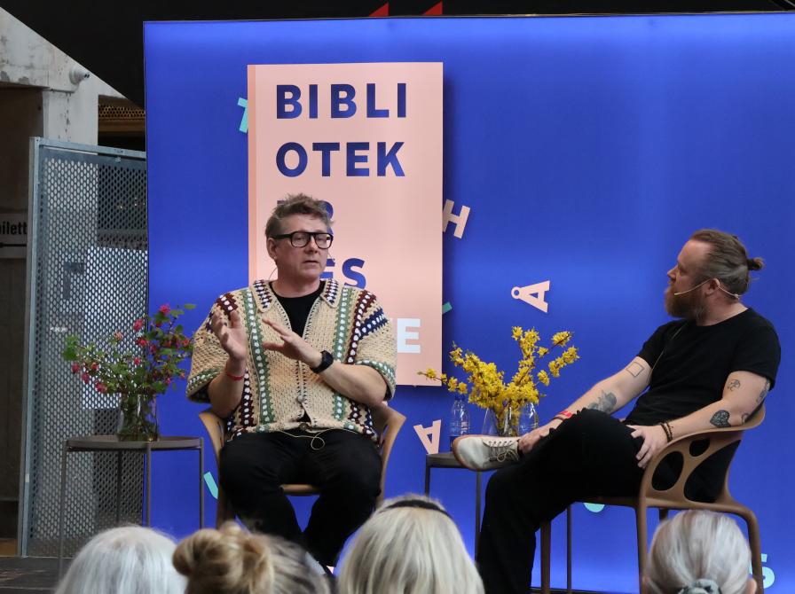 To mennesker, Jørgen (tv) og Teis (tv) sidder på en scene og taler foran et publikum